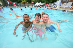 Young summer camp attendees swimming in an outdoor pool