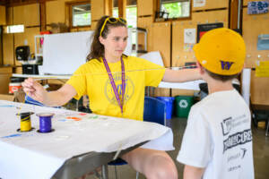 Camp counselor helping an attendee make a bracelet