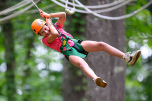 Young summer camp attendee on a ropes course in Wheeler Farm.